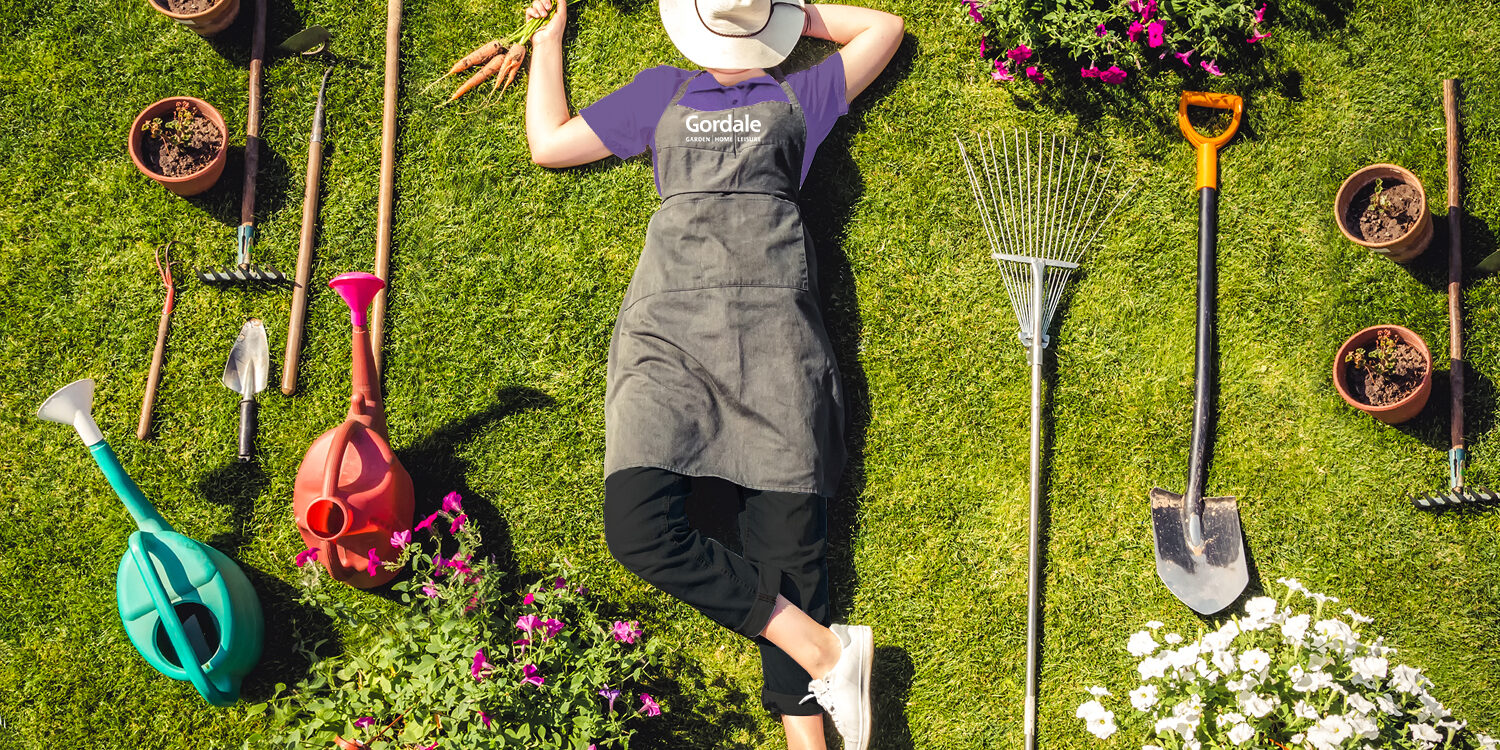 Gardener lying on grass surrounded by gardening tools