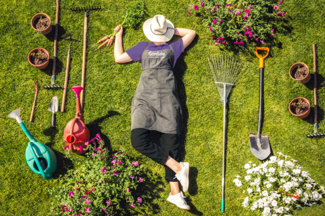 Gardener lying on grass surrounded by gardening tools