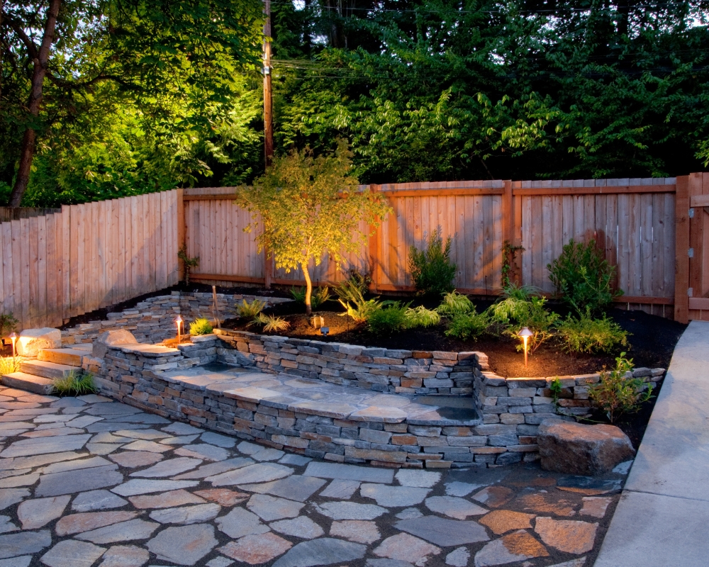 Rectangular garden with stone built seating area and planted border