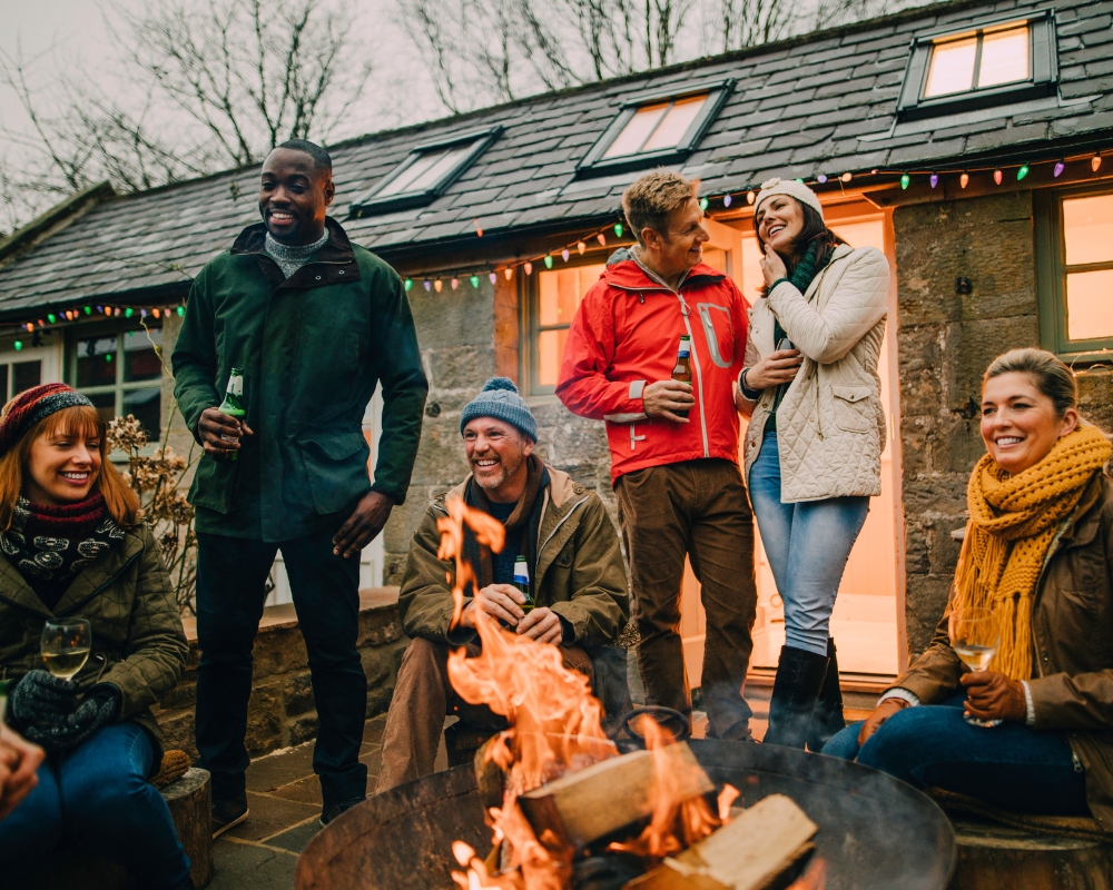 Friends socialising around a lit fire pit