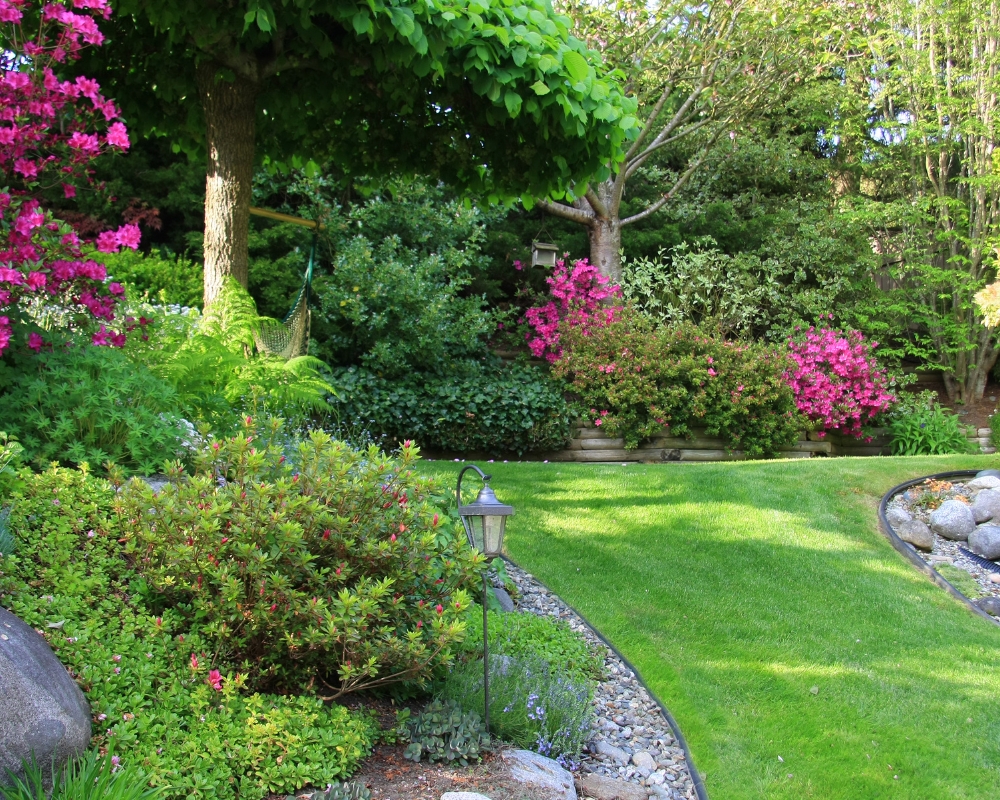 Curved borders in garden with hanging lantern stake light